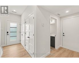 A white hallway with a glass door and a black trash can.