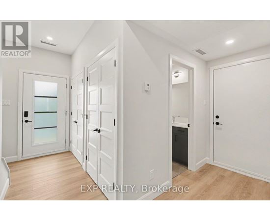A white hallway with a glass door and a black trash can.