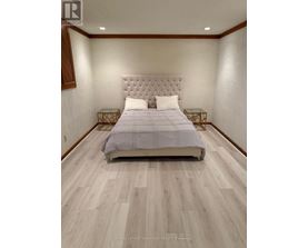 A bedroom with a large bed and wooden flooring.