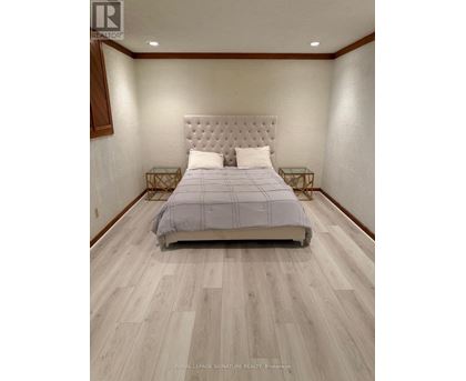 A bedroom with a large bed and wooden flooring.