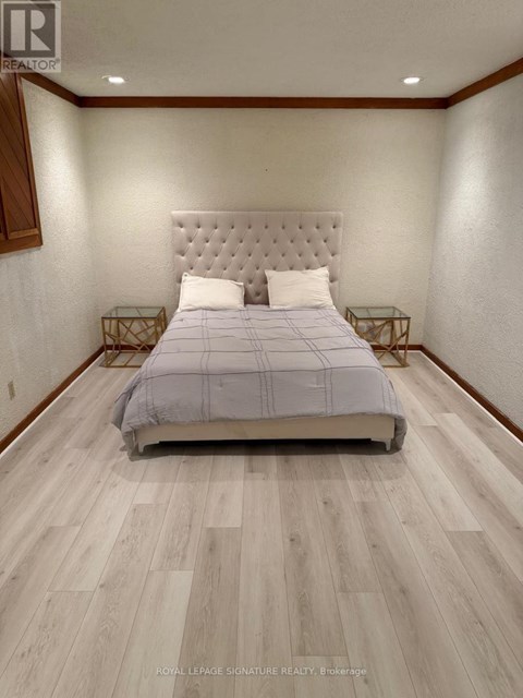 A bedroom with a large bed and wooden flooring.