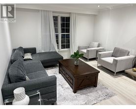 A living room with a grey sofa, a wooden coffee table, and a white chair.