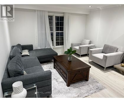 A living room with a grey sofa, a wooden coffee table, and a white chair.