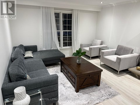 A living room with a grey sofa, a wooden coffee table, and a white chair.