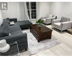 A living room with a grey couch, a wooden coffee table, and a white lamp.