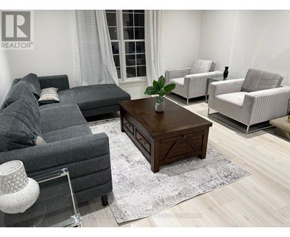 A living room with a grey couch, a wooden coffee table, and a white lamp.
