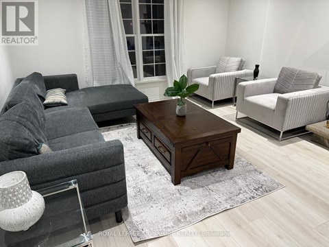 A living room with a grey couch, a wooden coffee table, and a white lamp.