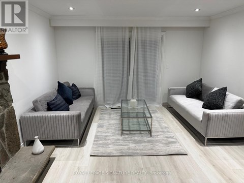 A modern living room with a glass coffee table and two grey sofas.