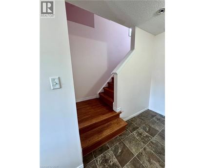 A staircase with a wooden handrail and tiled floor.