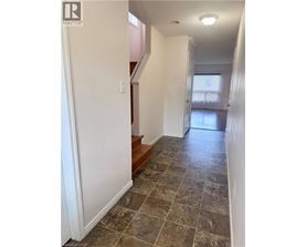 A hallway with tiled flooring and a staircase.