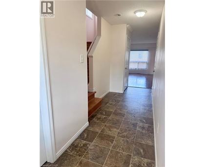 A hallway with tiled flooring and a staircase.