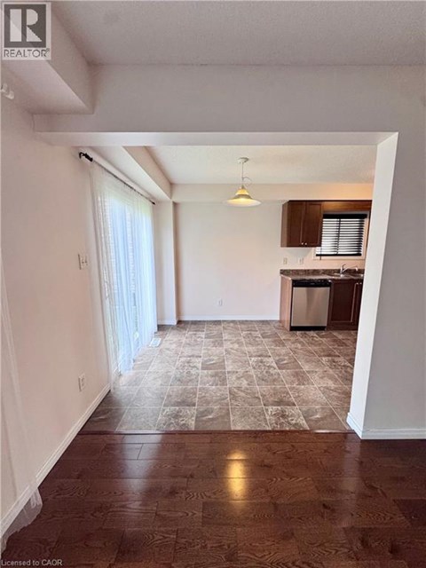 A room with a kitchen in the background and a tiled floor.