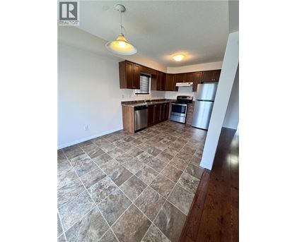 A kitchen with tile flooring and wooden cabinets.