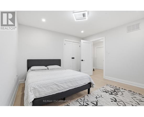 A bedroom with a large bed and a rug on the floor.