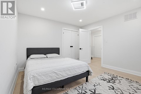 A bedroom with a large bed and a rug on the floor.