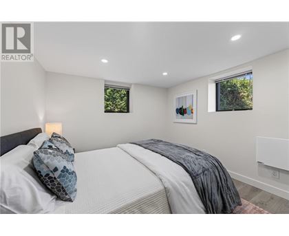 A bedroom with a bed, pillow, blanket, and two windows.