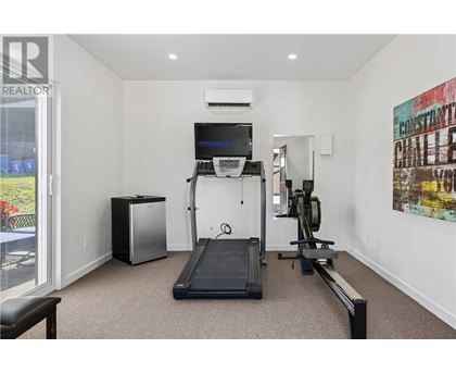 A room with a treadmill, a television, and a weight machine.