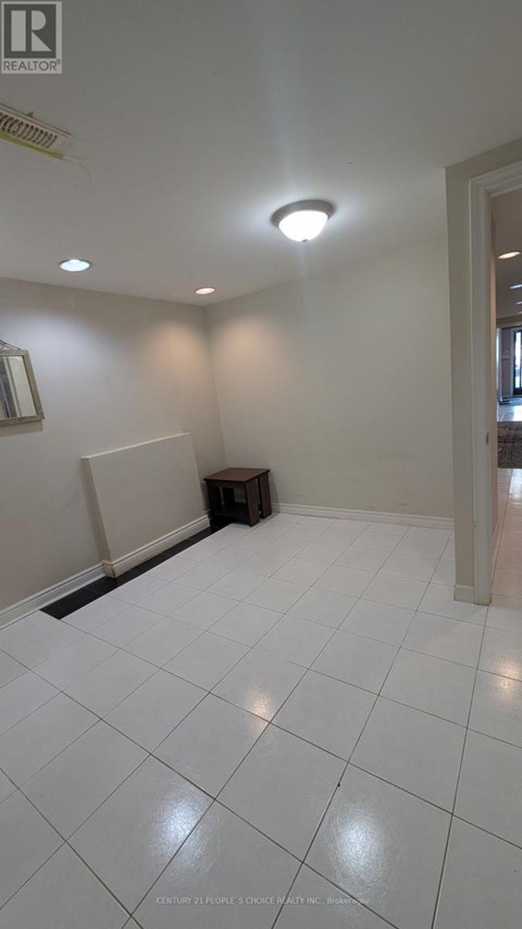 A white tiled room with a small table and a painting on the wall.