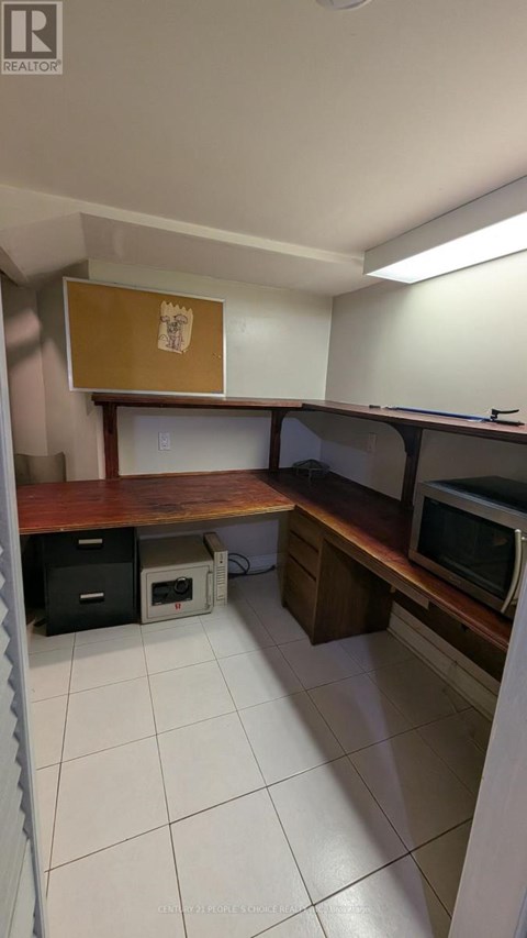A kitchen with white tiles and a microwave on the counter.