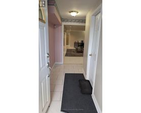 A hallway with a rug on the floor and a door on the left.