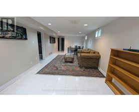 A living room with a rug, a couch, and a TV mounted on the wall.