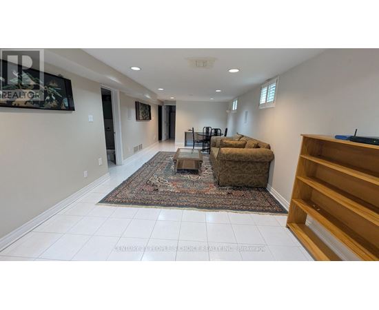 A living room with a rug, a couch, and a TV mounted on the wall.