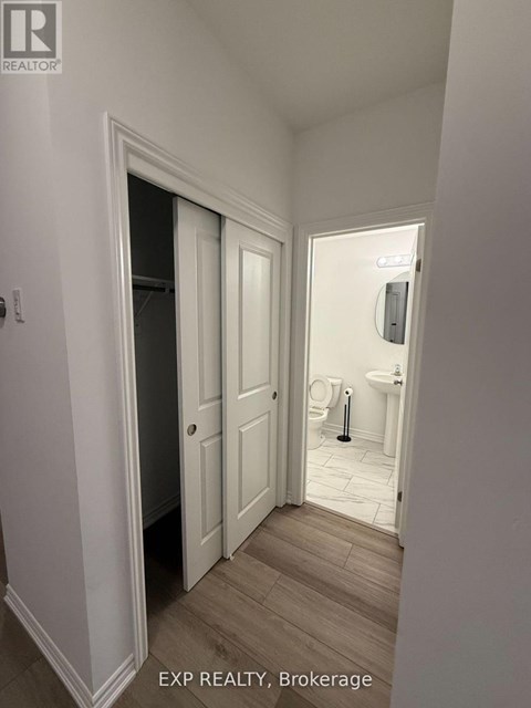 A hallway with a door on the left and a bathroom on the right.