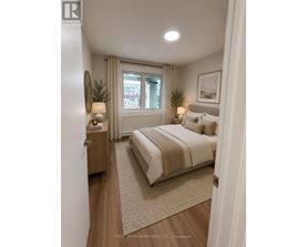 A bedroom with a large bed, a nightstand with a lamp, and a framed picture on the wall.