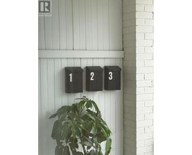 A plant is in front of a wall with three black boxes with the numbers 1, 2 and 3 on them.