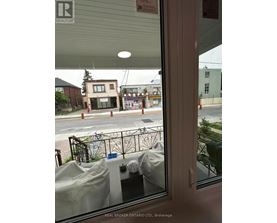 A view from inside a building looking out to a street with a Real Broker sign.