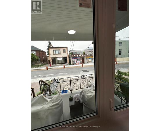 A view from inside a building looking out to a street with a Real Broker sign.