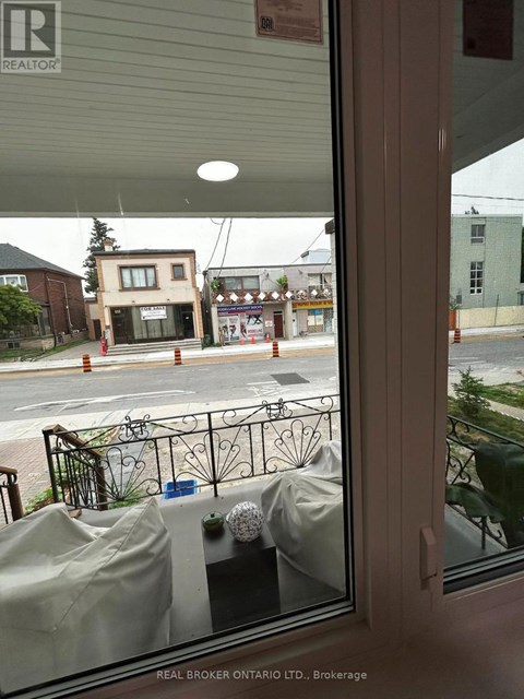 A view from inside a building looking out to a street with a Real Broker sign.