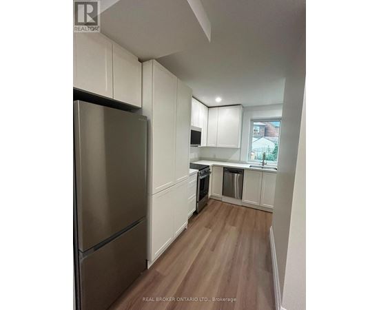 A kitchen with white cabinets and a stainless steel refrigerator.