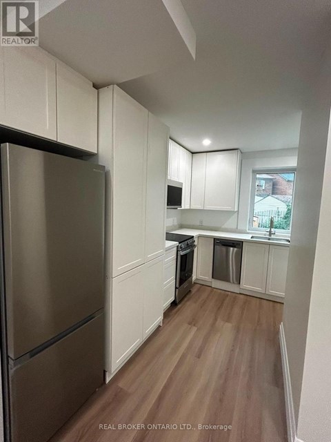 A kitchen with white cabinets and a stainless steel refrigerator.