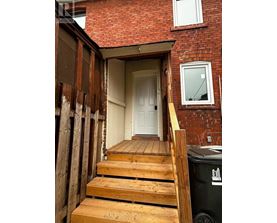 A wooden staircase leads to a white door in a red brick house.