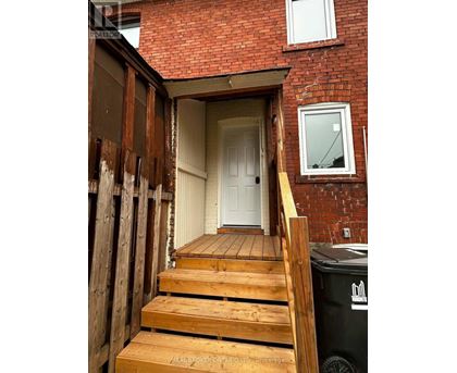 A wooden staircase leads to a white door in a red brick house.