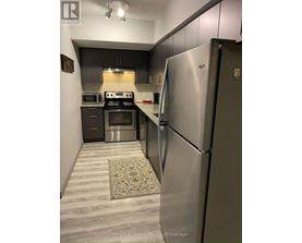 A kitchen with a stainless steel refrigerator and a stove top oven.