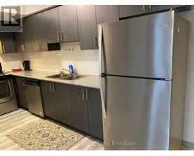 A kitchen with a stainless steel refrigerator and cabinets.