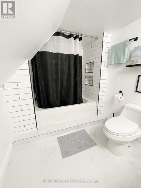 A white toilet in a bathroom with a black shower curtain.