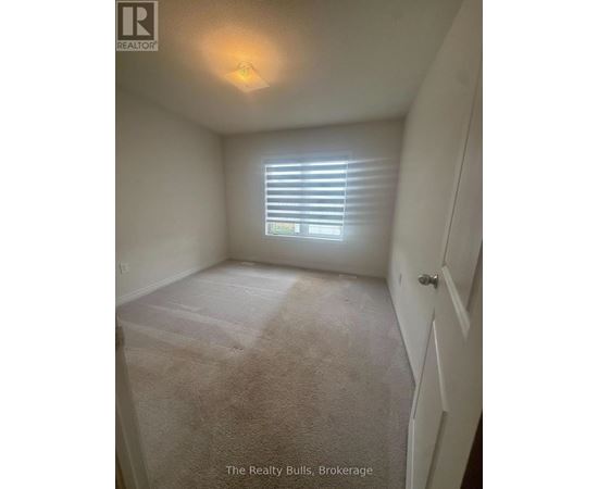 A bedroom with a carpeted floor and a window with blinds.