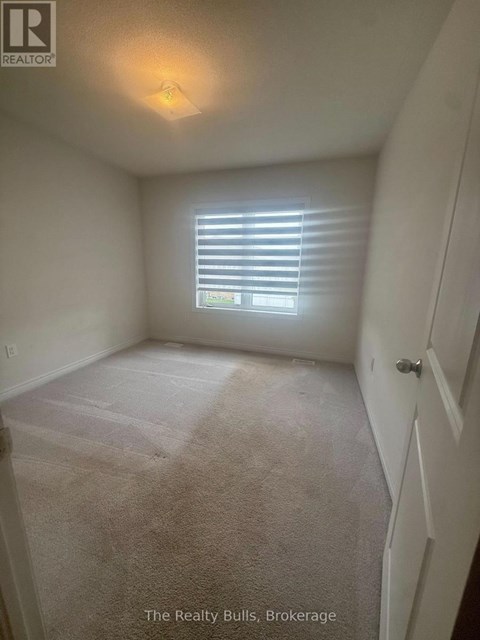 A bedroom with a carpeted floor and a window with blinds.