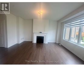 A spacious room with a fireplace and wood flooring.