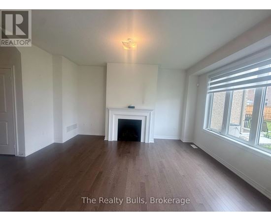 A spacious room with a fireplace and wood flooring.
