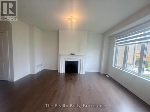 A spacious room with a fireplace and wood flooring.