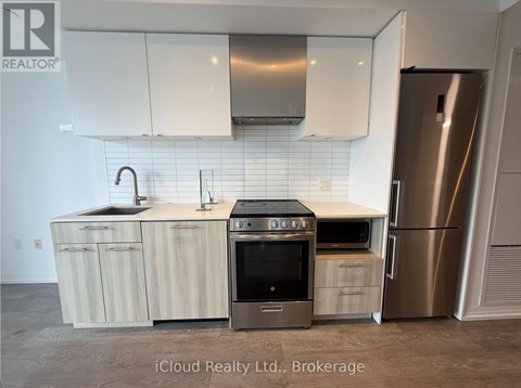 A kitchen with a stainless steel refrigerator and wooden cabinets.