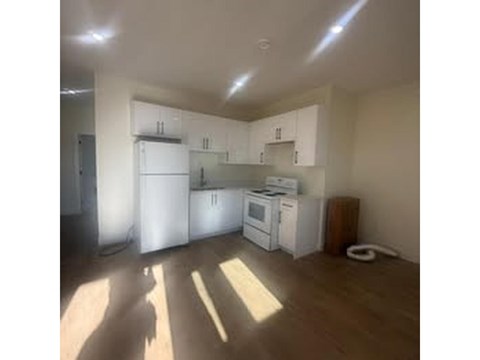 A kitchen with white appliances and wooden floors.