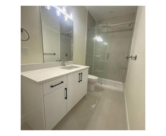A white bathroom with a sink, mirror, and shower.