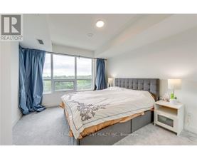 A bedroom with a large bed and a window with blue curtains.