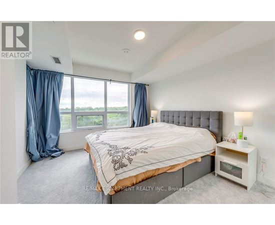 A bedroom with a large bed and a window with blue curtains.