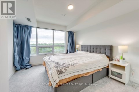 A bedroom with a large bed and a window with blue curtains.